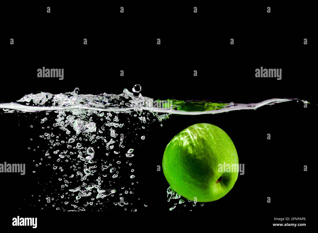 green apple falls into water on black background Stock Photo