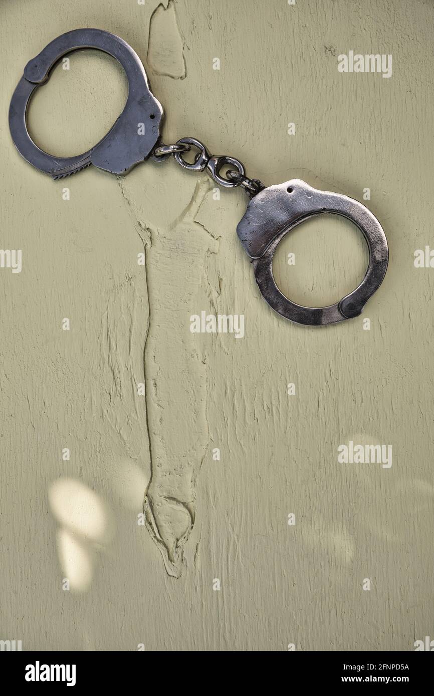 Directly above of locked handcuffs isolated on wooden textured background. Concept of bondage, kinky, restraint, guilt, domination, authority Stock Photo