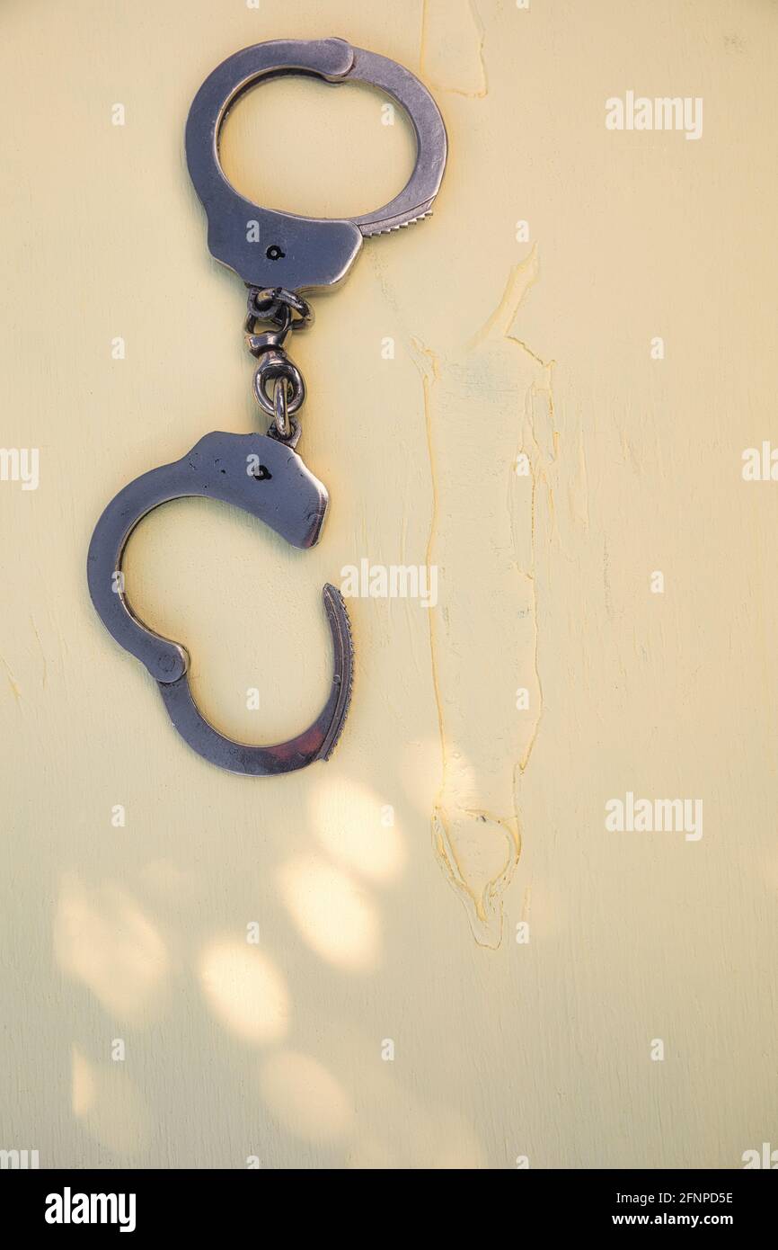 Directly above of pair of handcuffs one locked one unlocked isolated on yellow textured background. Concept of security, law, crime, justice, capture Stock Photo