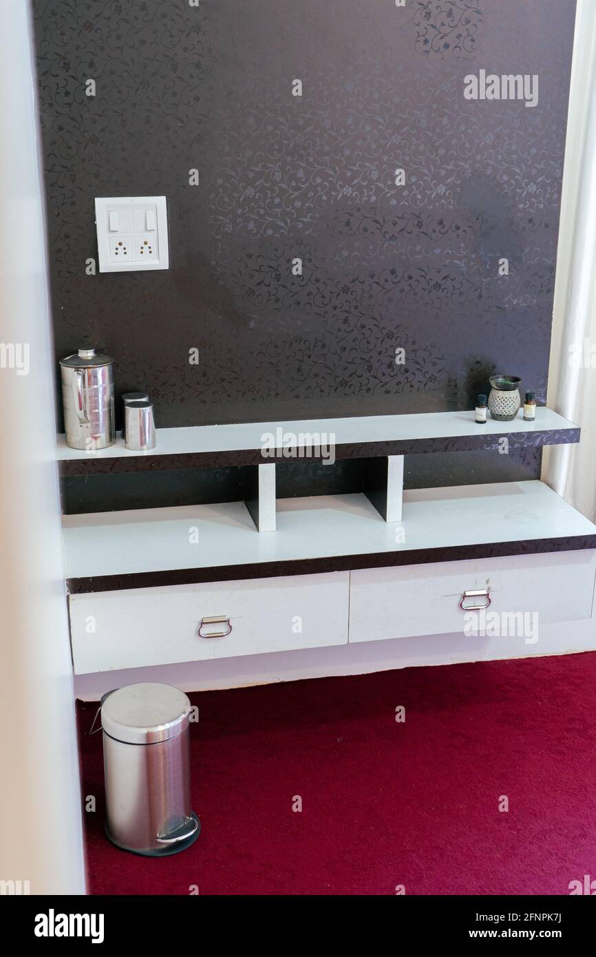 Vertical shot of a modern white shelf hanging on a black wall Stock