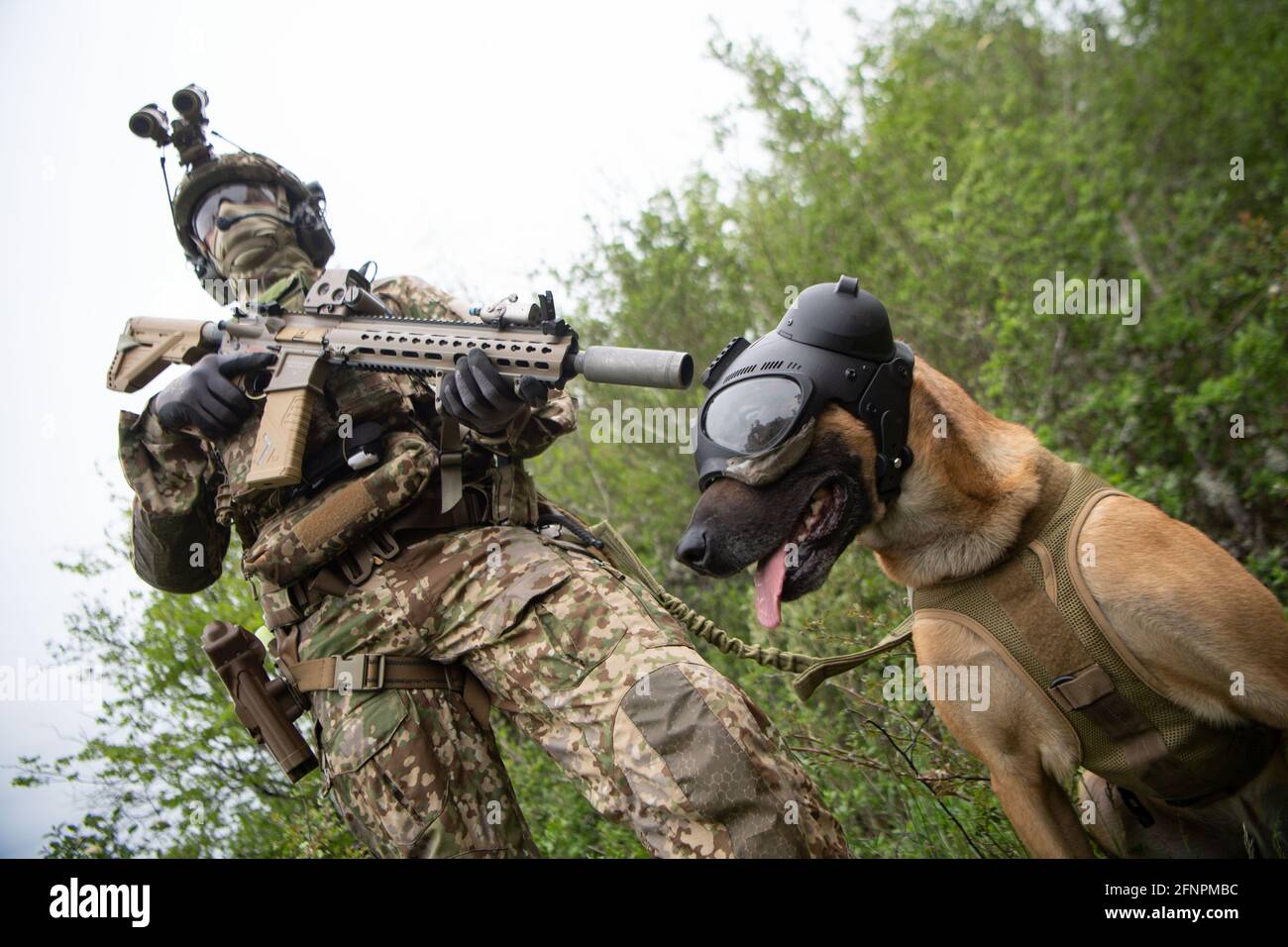 Calw, Germany. 10th May, 2021. A soldier of the German Armed Forces Special Forces Command (KSK) stands in a meadow with an access service dog wearing eye and ear protection during a video shoot for Armed Forces Day. Credit: Marijan Murat/dpa/Alamy Live News Stock Photo