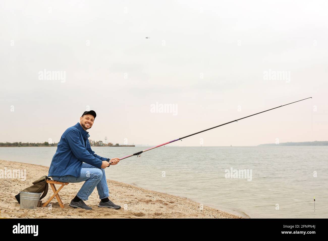 Man fishing on river bank Stock Photo - Alamy