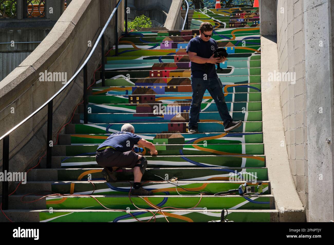 Graphic workers doing paint touch up on urban designed public stairs with image of old Ottawa. Stock Photo