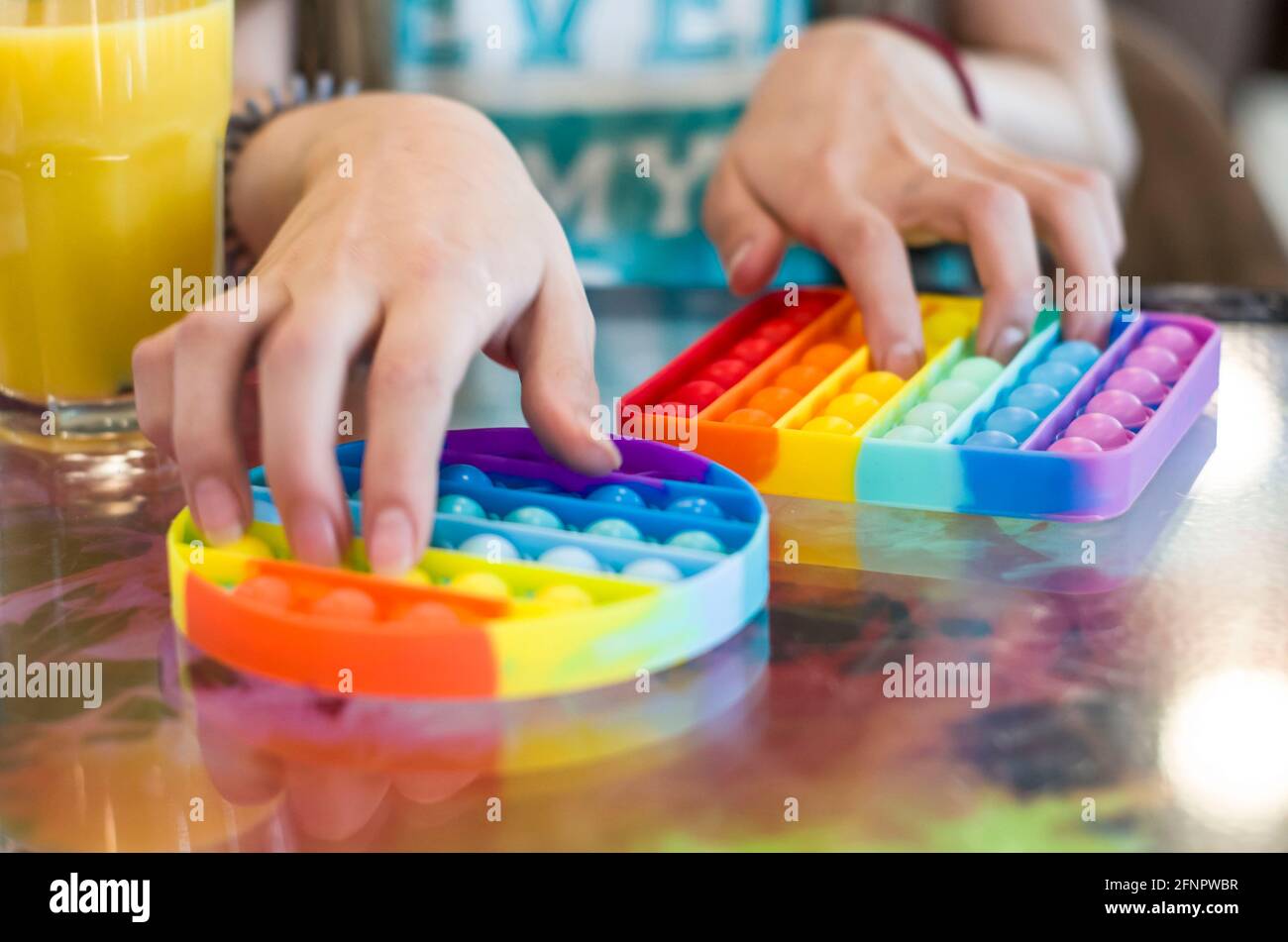 Pop it children's anti-stress toy made of silicone for tactile development. Photo of children's hands on a blurred background. Stock Photo