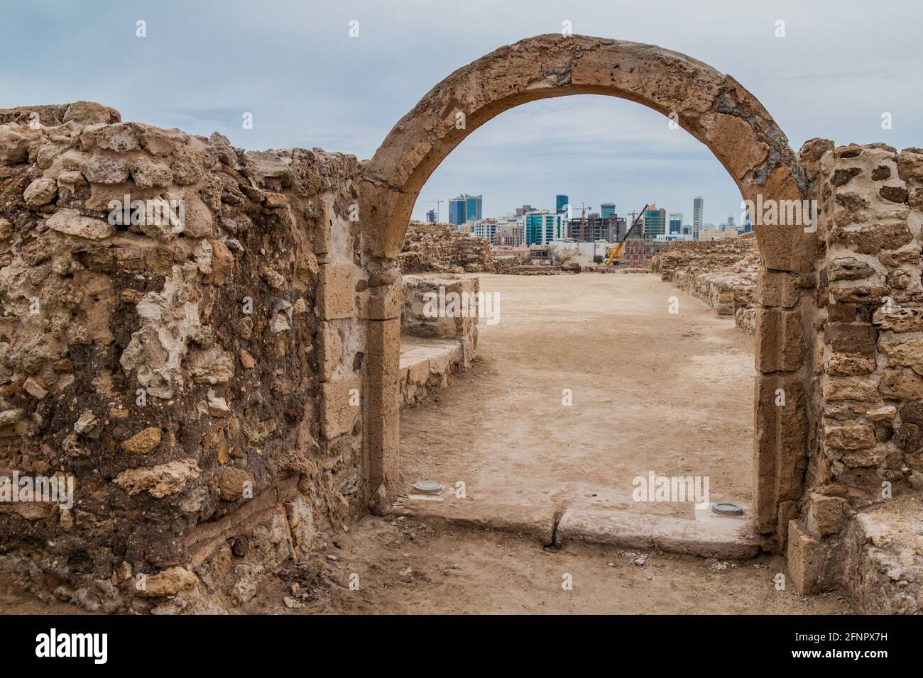 Ruins of Bahrain Fort Qal'at al-Bahrain and Manama Skyline in Bahrain Stock Photo
