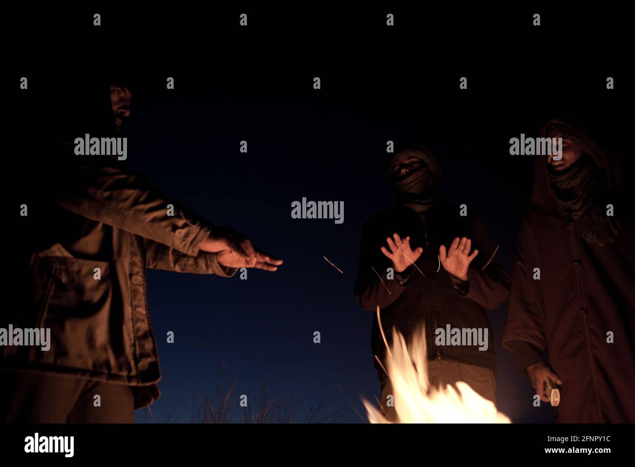 Liberated Territories, Western Sahara. A group of Sahrawi men warm themselves by the fire, getting ready to spend the night in the desert. Stock Photo