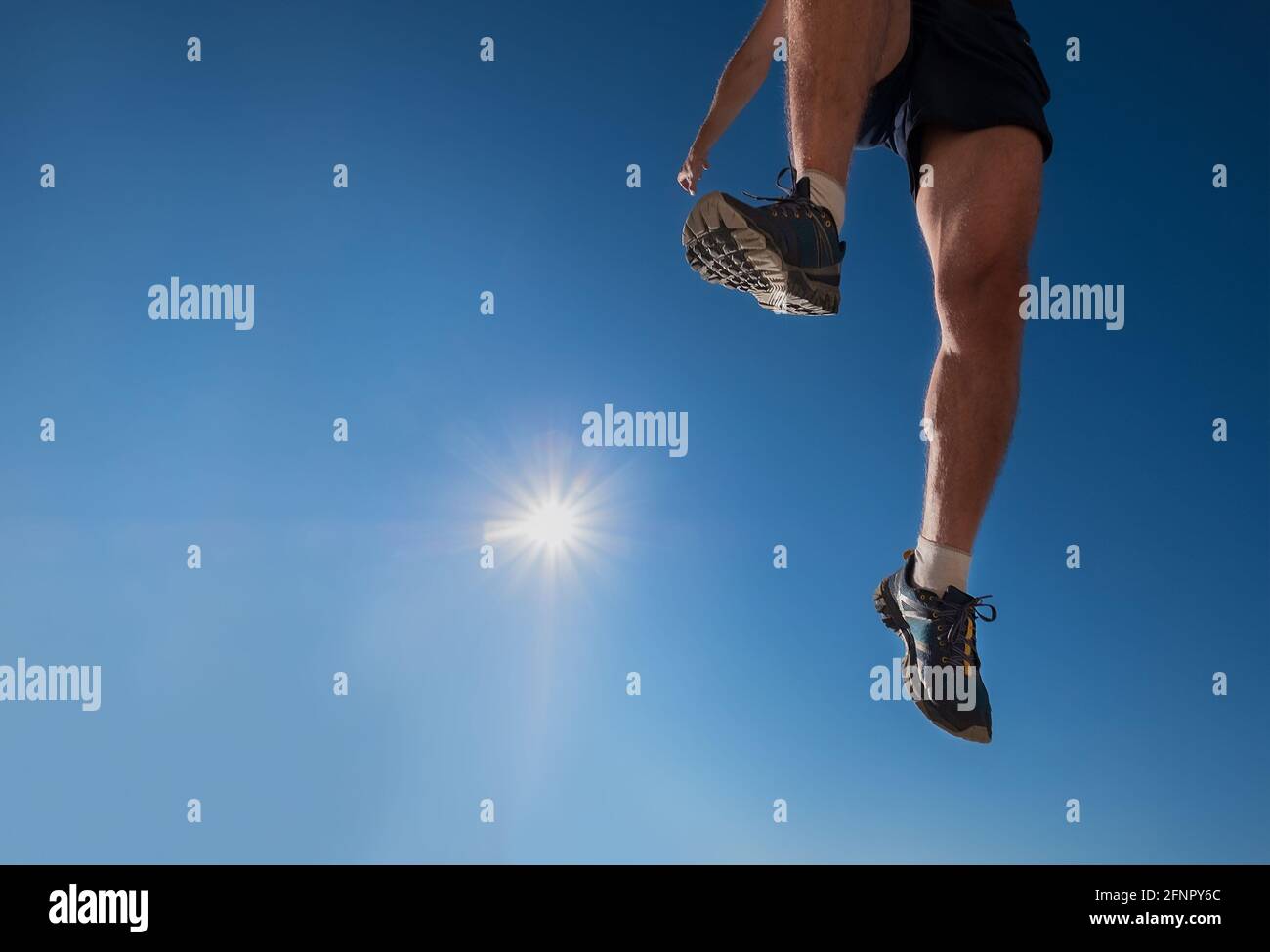 Flying jumping runner on the blue sky with bright sun background. and over the  Sporty Active people activities a wide-angle concept image. Stock Photo