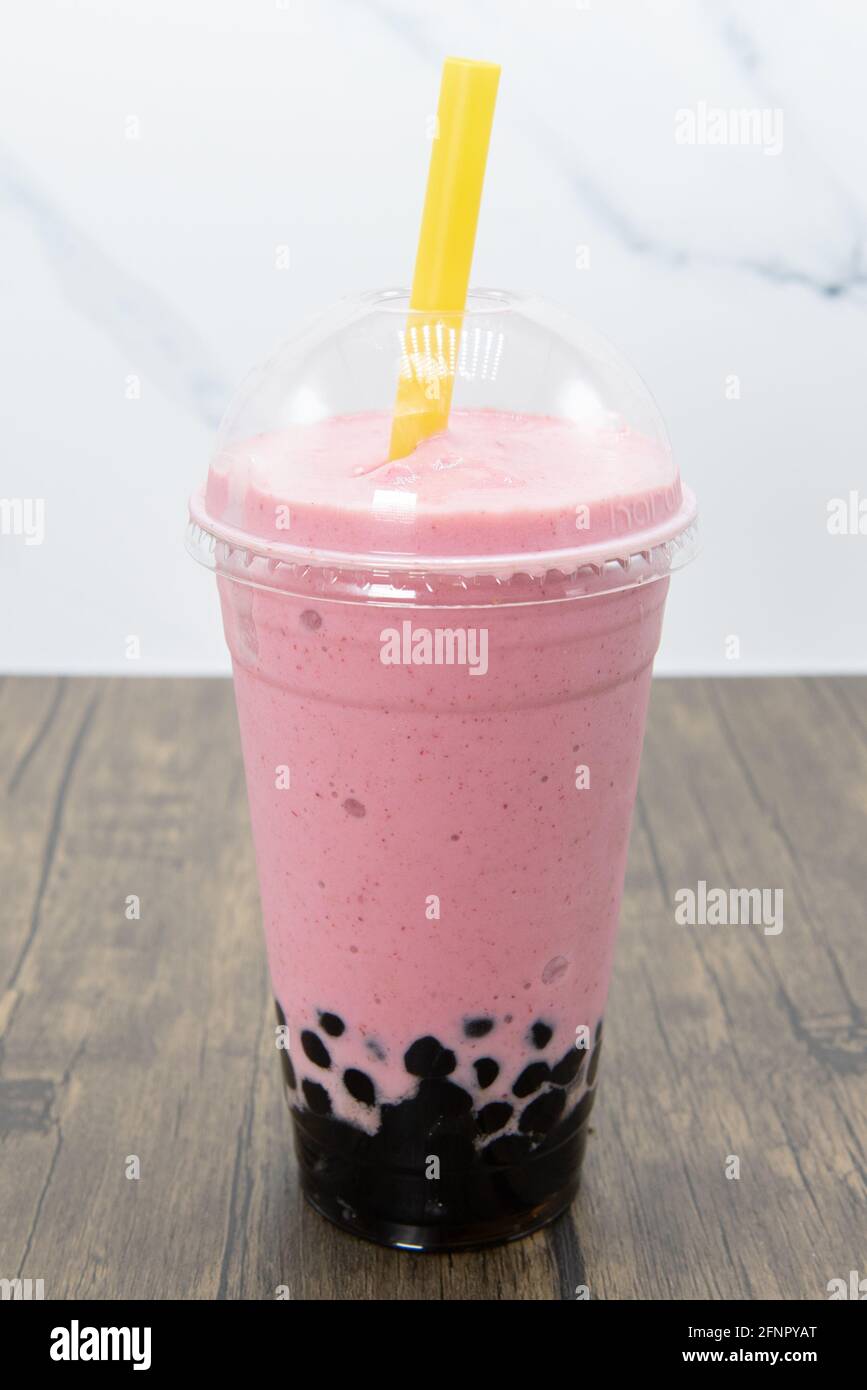 Strawberry banana boba smoothie served cold with a thick straw for the tapioca balls to easily pass. Stock Photo