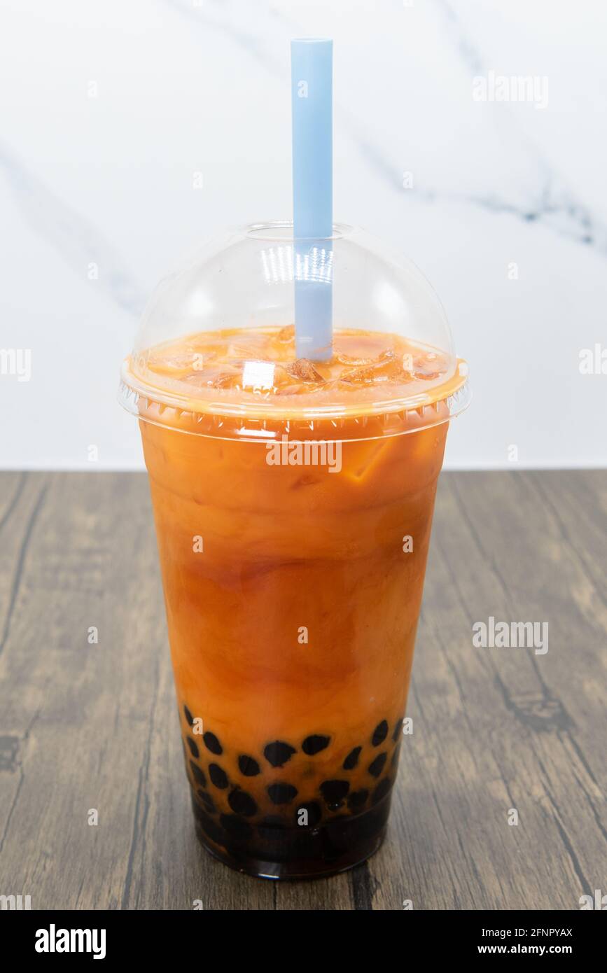 Thai tea boba smoothie served cold with a thick straw for the tapioca