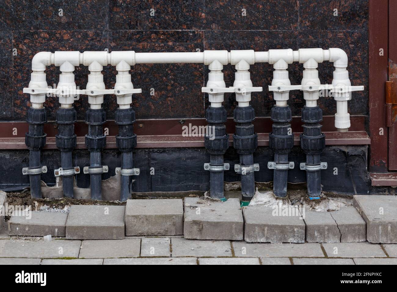 white plastic water pipe with many branches and shutoff taps for floor