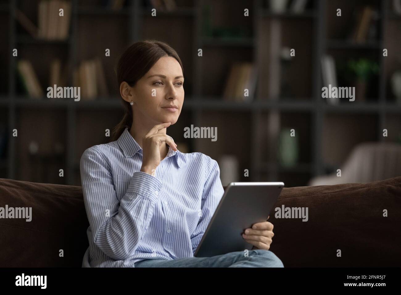 Pensive young female hold tablet think on message received Stock Photo