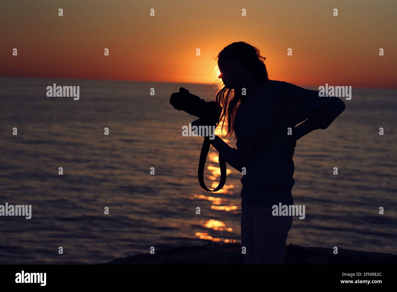 woman at sunset near the sea with a camera in hand Stock Photo - Alamy