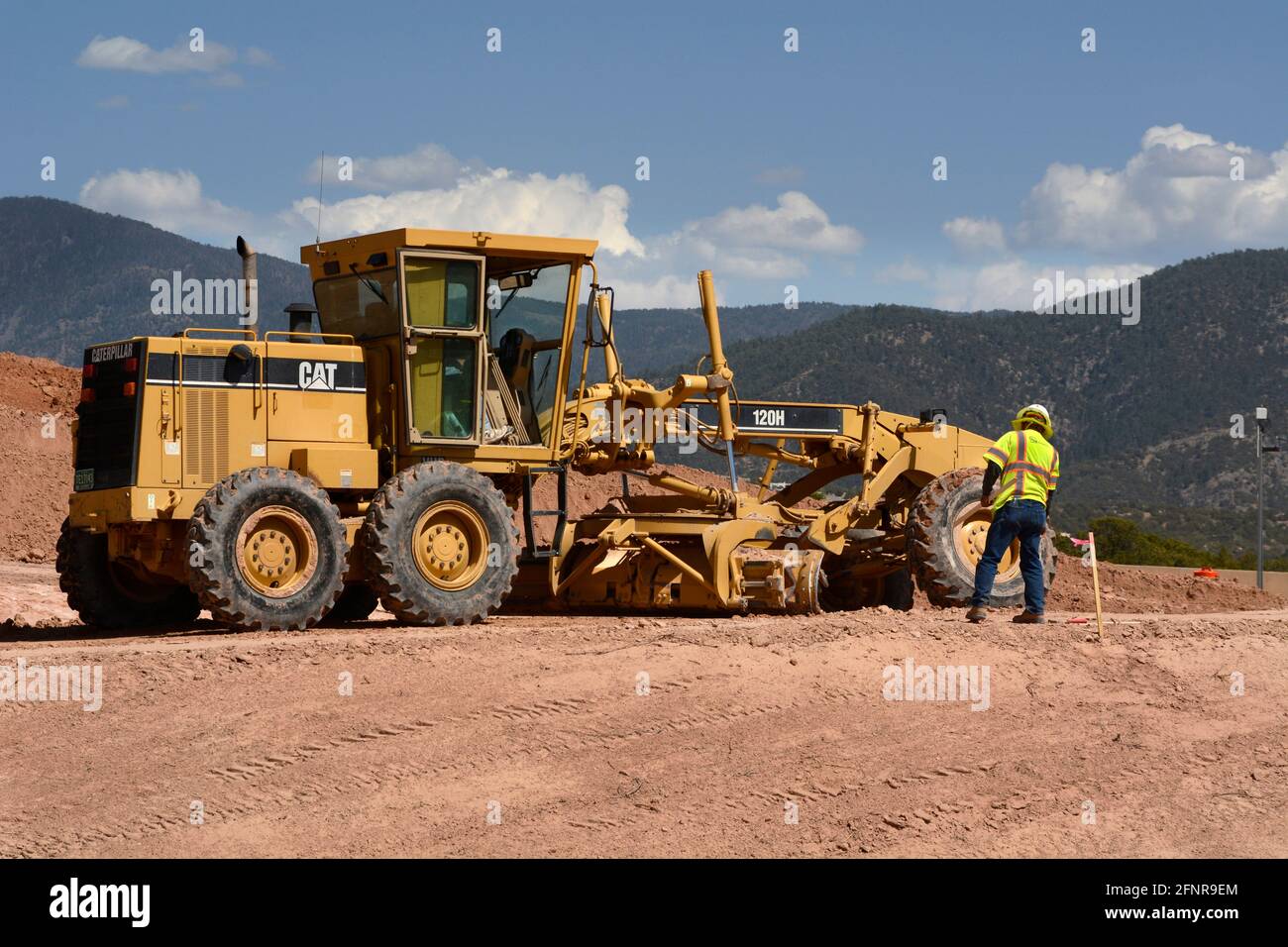 A heavyequipment operator uses a Caterpillar 120H motor grader to move