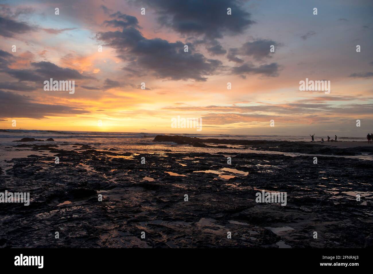Colorful sunset over beach with tidepools in rocks h in  Costa Rica Stock Photo