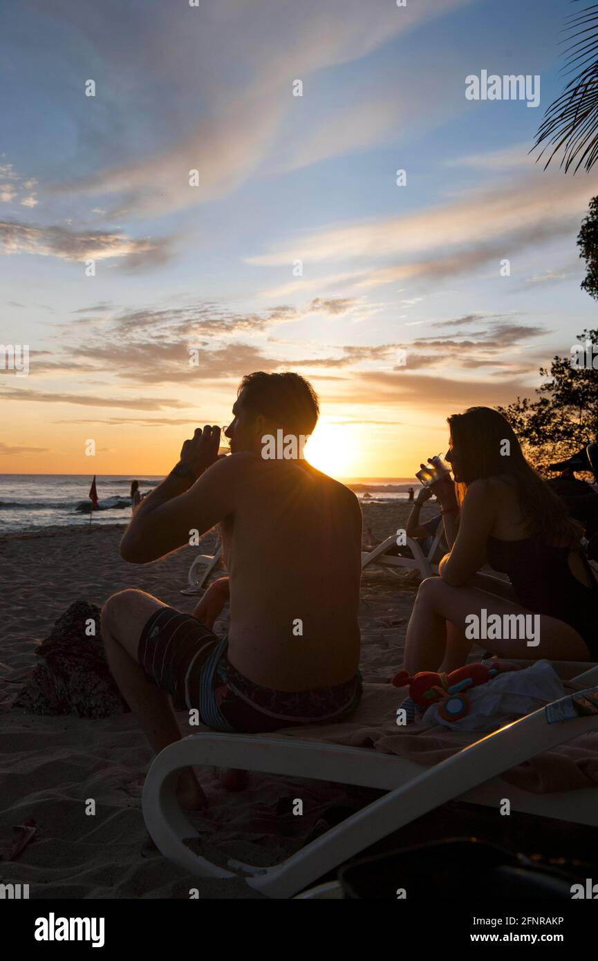 Couple enjoying a drink on the beach at sunset in Costa Rica Stock Photo