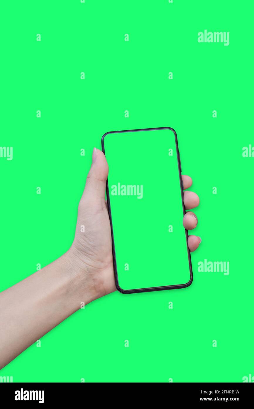Hand holding smartphone with green screen isolated on green background ...