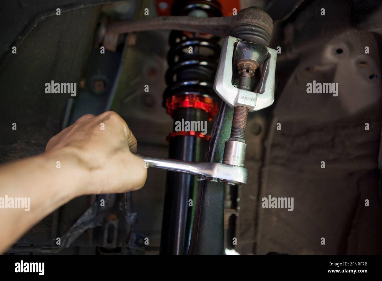 Auto repairman using a ball joint tool (ball joint removal) on a car suspension - USA Stock Photo