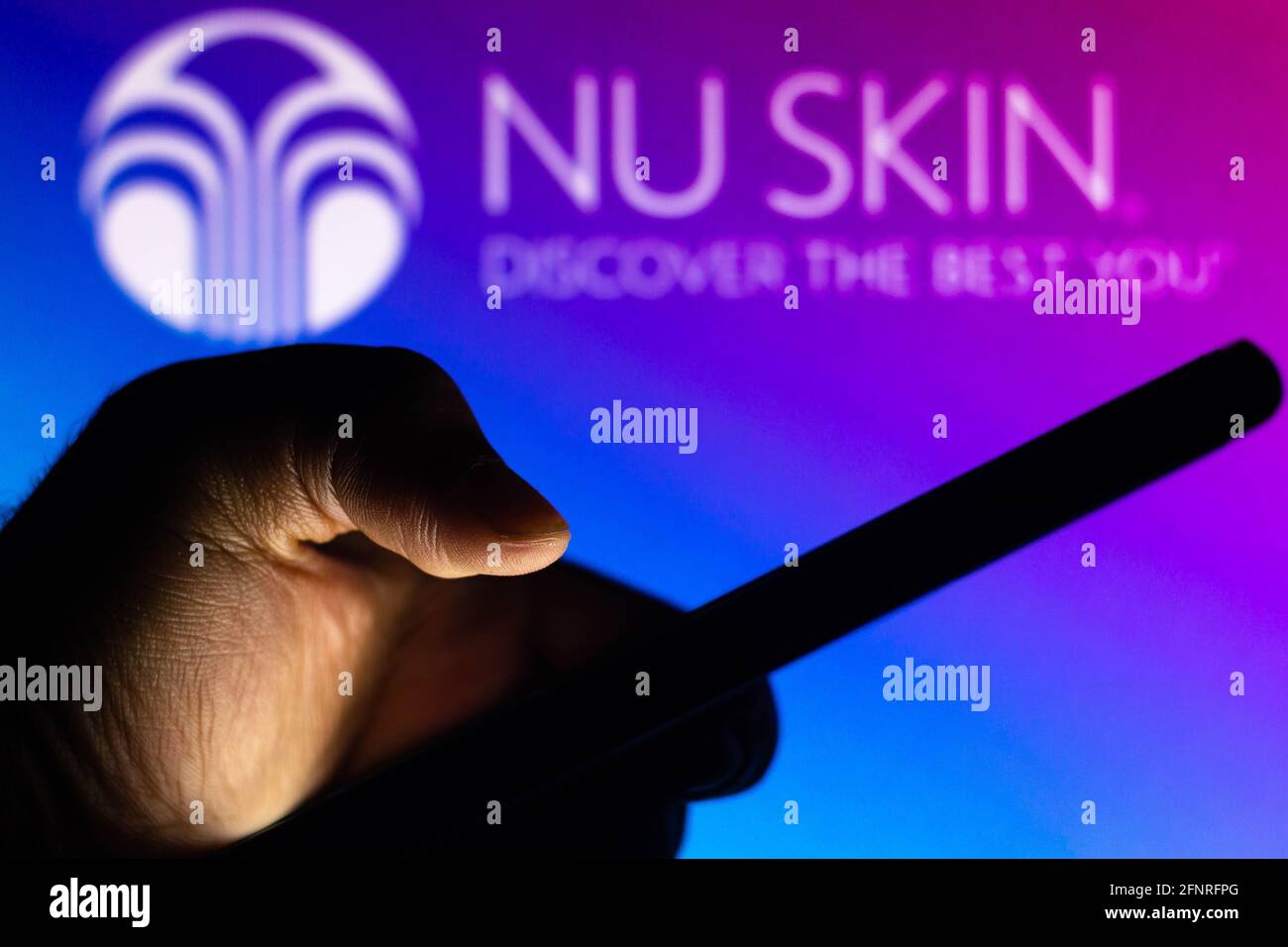 Brazil. 13th May, 2021. In this photo illustration the Nu Skin Enterprises logo seen in the background of a silhouette hand holding a mobile phone. Credit: Rafael Henrique/SOPA Images/ZUMA Wire/Alamy Live News Stock Photo