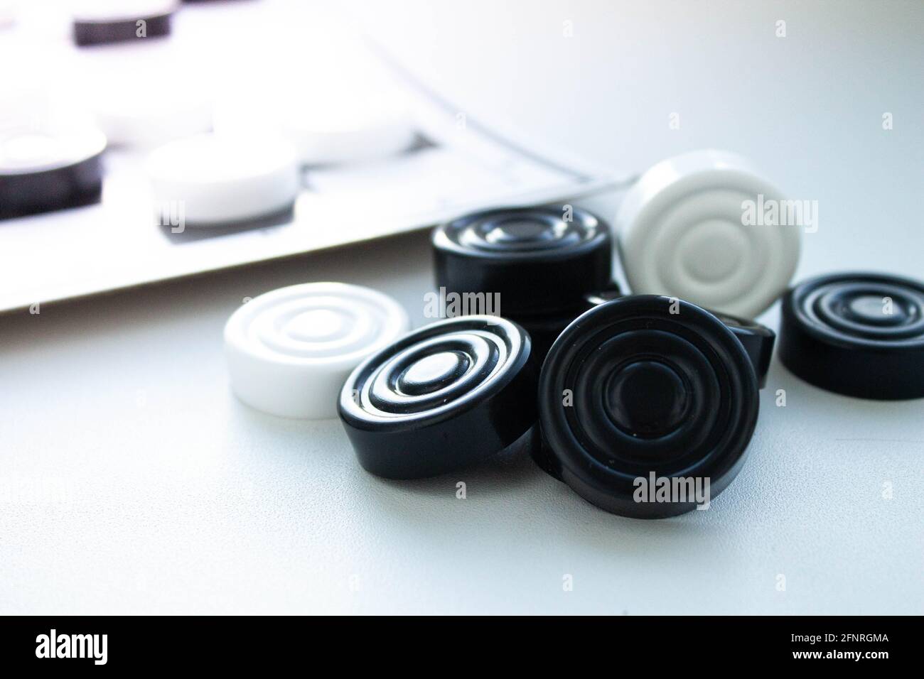 Board game of checkers. Black and white chips for the game. Chess field. Checkers move close-up. Checker in hand. Stock Photo