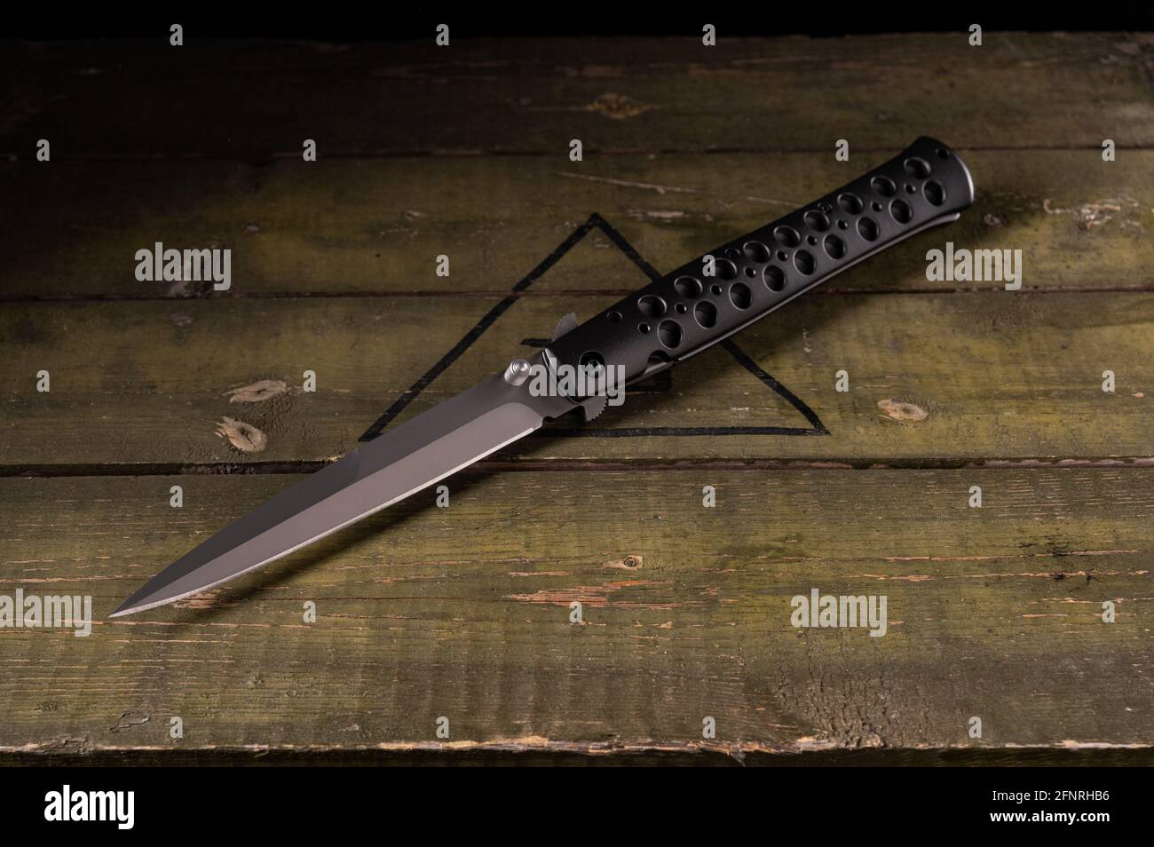 Long and narrow folding knife. Knife with holes in the handle. View of the knife at an angle