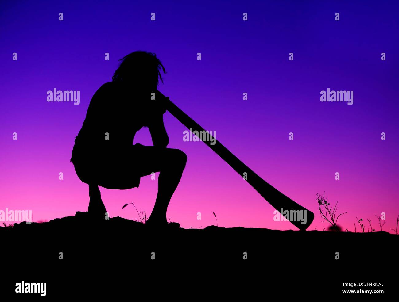 Aboriginal playing Didgeridoo at sunset. Alice Springs. Australia Stock
