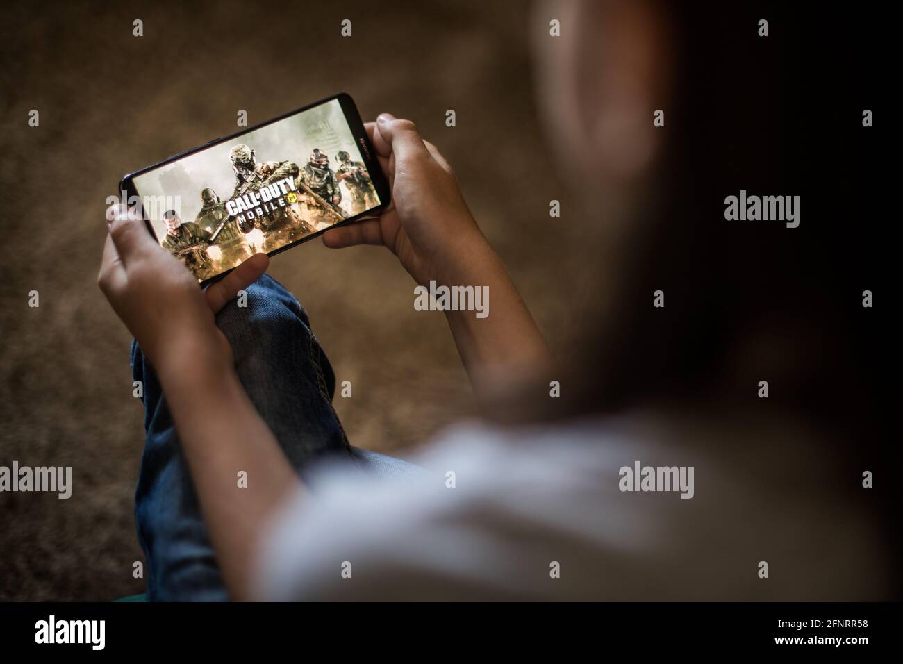 Bucharest, ROMANIA - May 10, 2021: Illustrative editorial concept image of a child playing Call of Duty game on a mobile phone. Stock Photo