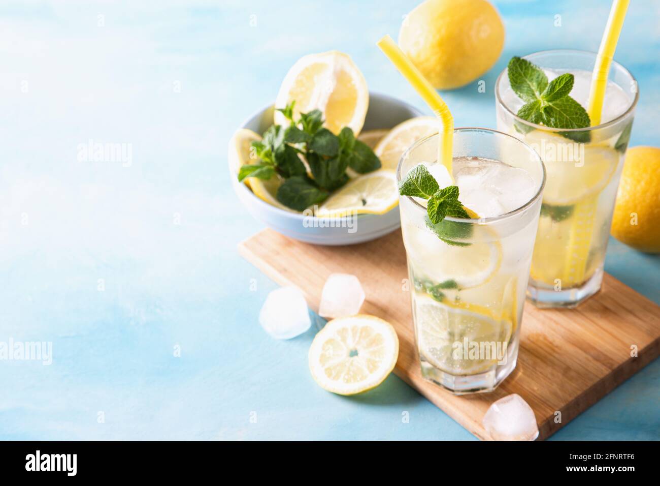 https://c8.alamy.com/comp/2FNRTF6/two-glass-with-lemonade-or-mojito-cocktail-with-lemon-and-mint-cold-refreshing-drink-or-beverage-with-ice-on-blue-background-copy-space-2FNRTF6.jpg