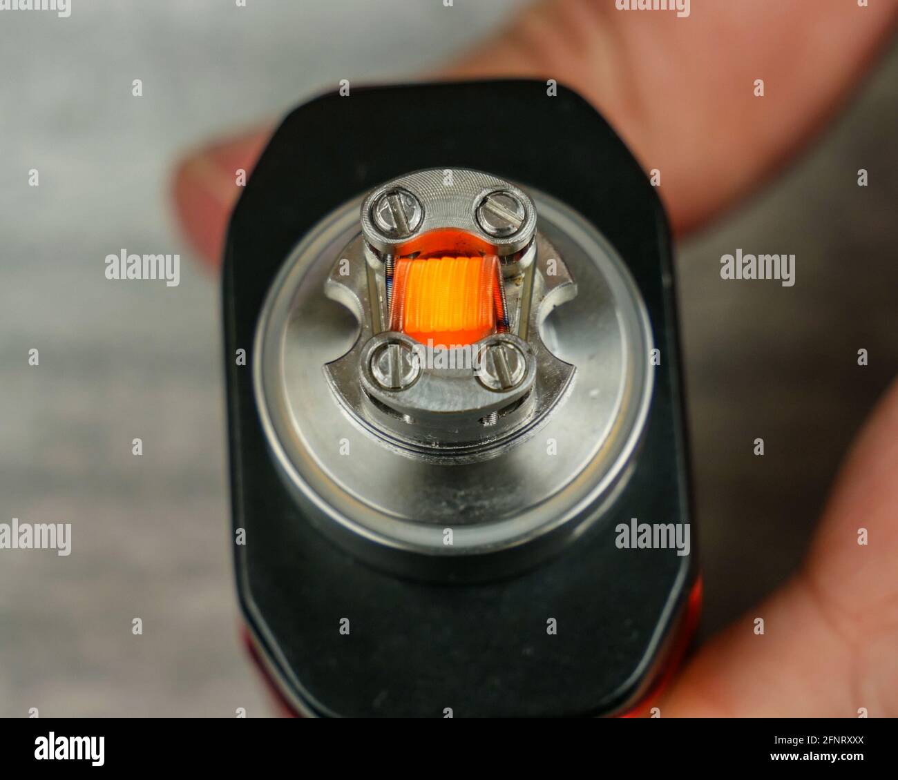 Slightly glowing coil in the atomizer for vaping. Stock Photo