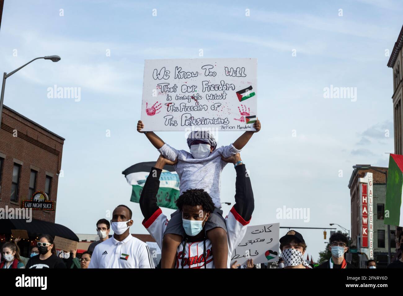 Columbus, United States. 18th May, 2021. Demonstrator marches in solidarity with Palestine while carrying a boy on his shoulders holding a sign quoting Nelson Mandela and his take on the Israel Palestine struggle during the demonstration. Demonstrators gathered at the Ohio Statehouse to protest against Israel's occupation of Palestine. (Photo by Stephen Zenner/SOPA Images/Sipa USA) Credit: Sipa USA/Alamy Live News Stock Photo