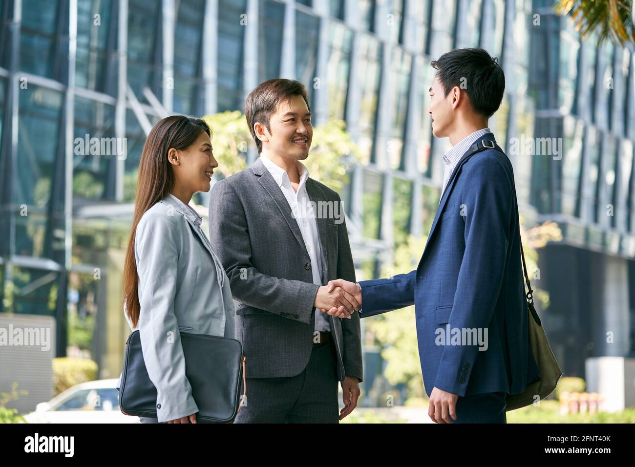 asian business associates meeting in the street in downtown financial district shaking hands Stock Photo