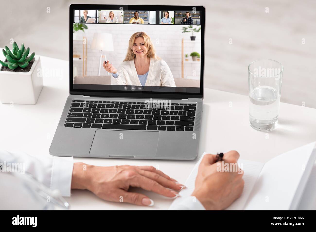 Young business lady having online group conference with her work colleagues on laptop from home office Stock Photo