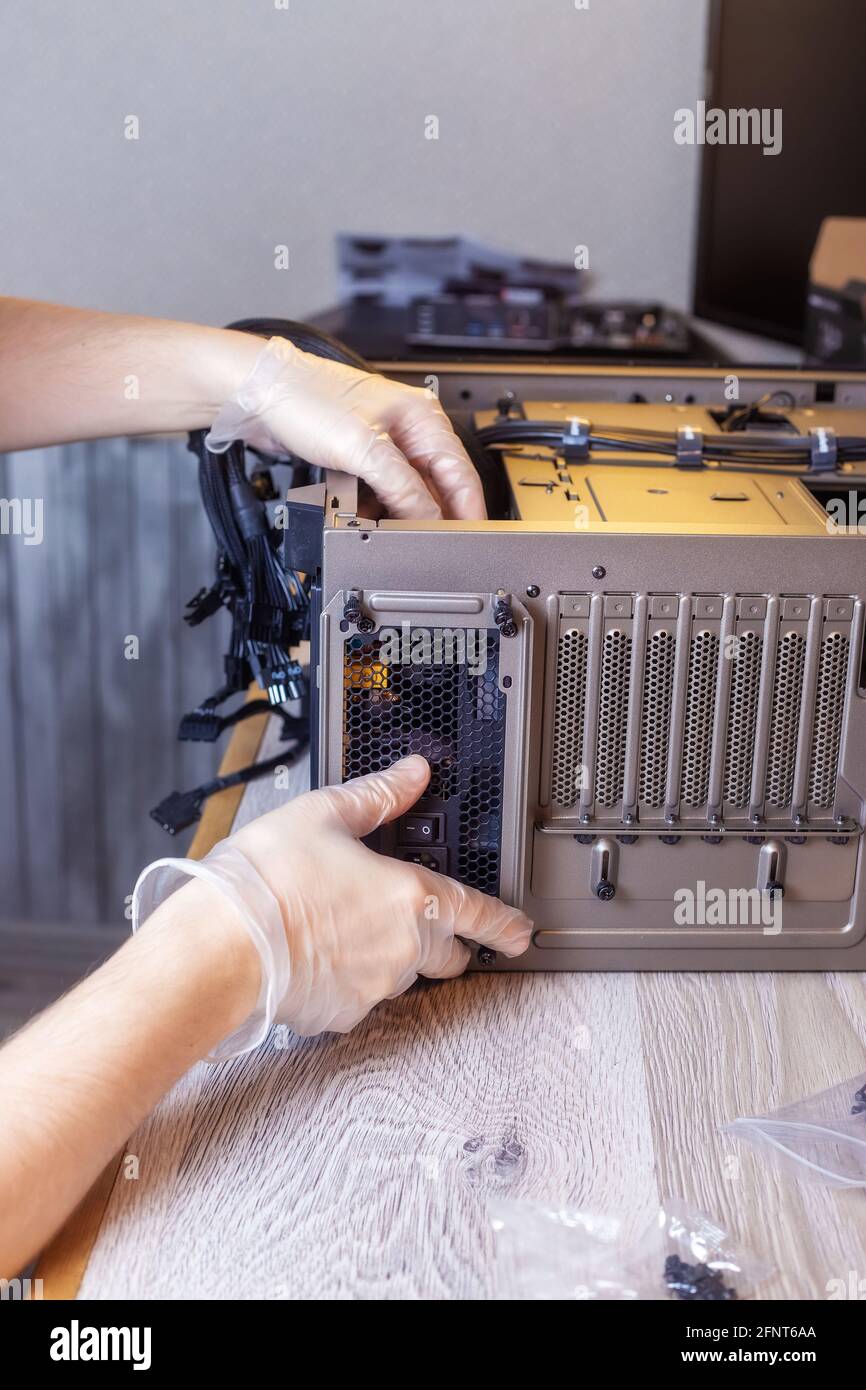 Technician is installing a new power supply into a computer Stock Photo