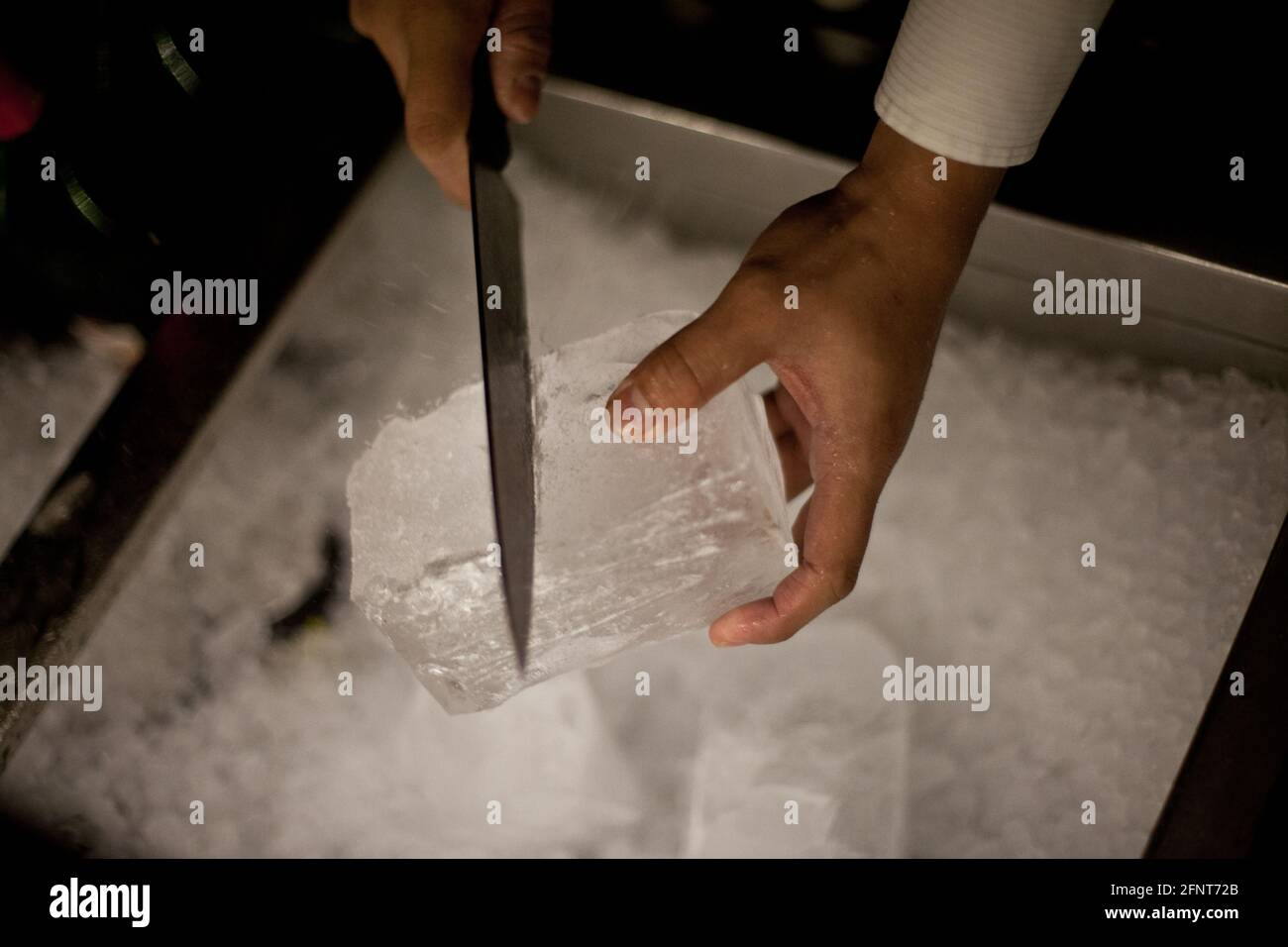 A barman carving ice  for cocktails at the Blind Pig, in Makati, Metro Manila. A bar in the tradition of the speakeasy bars during the prohibition. Stock Photo