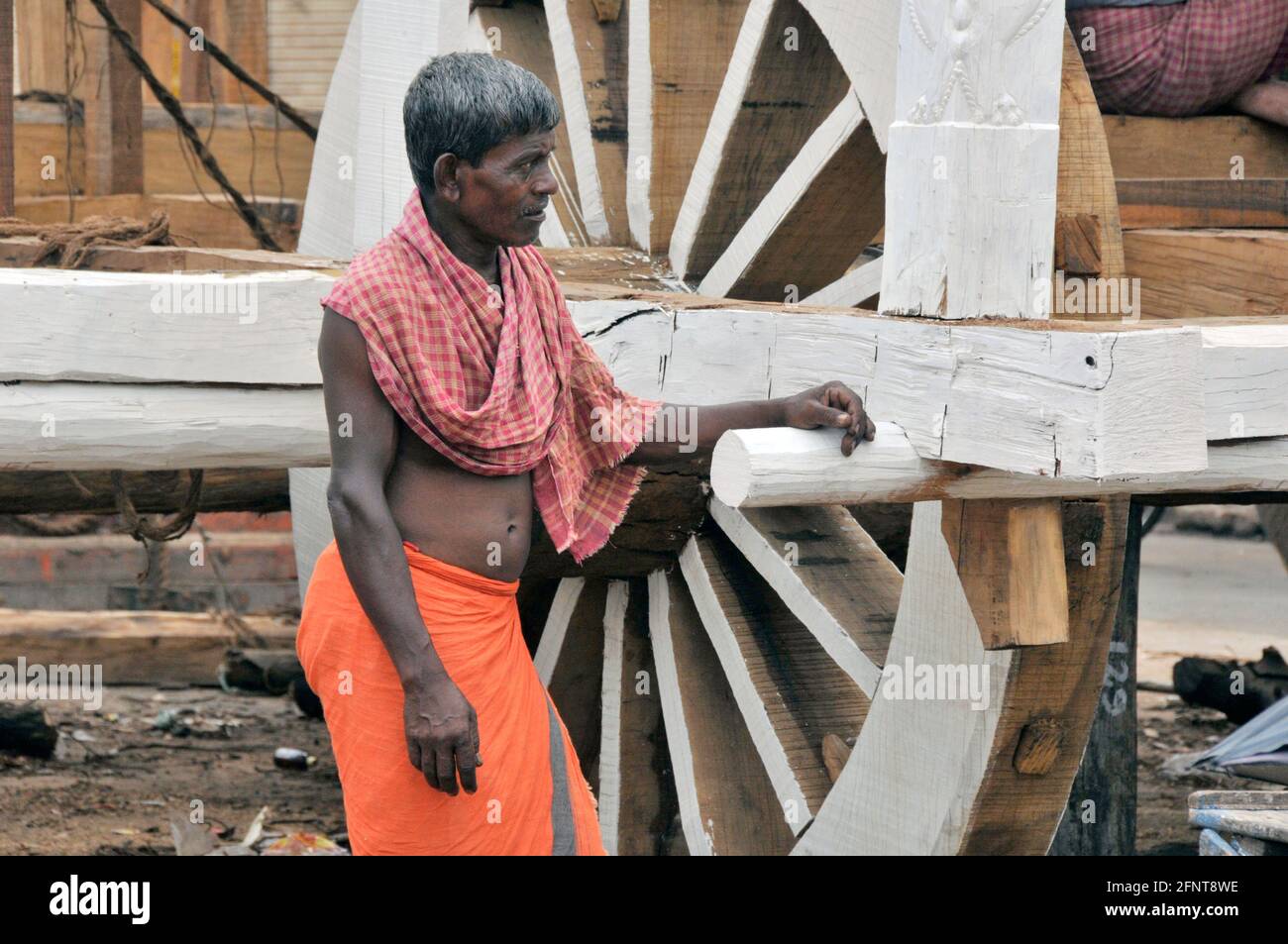 An artist stands in front of the half-finished chariot. Before the chariot festival, work is underway to make the chariot at Puri. Stock Photo