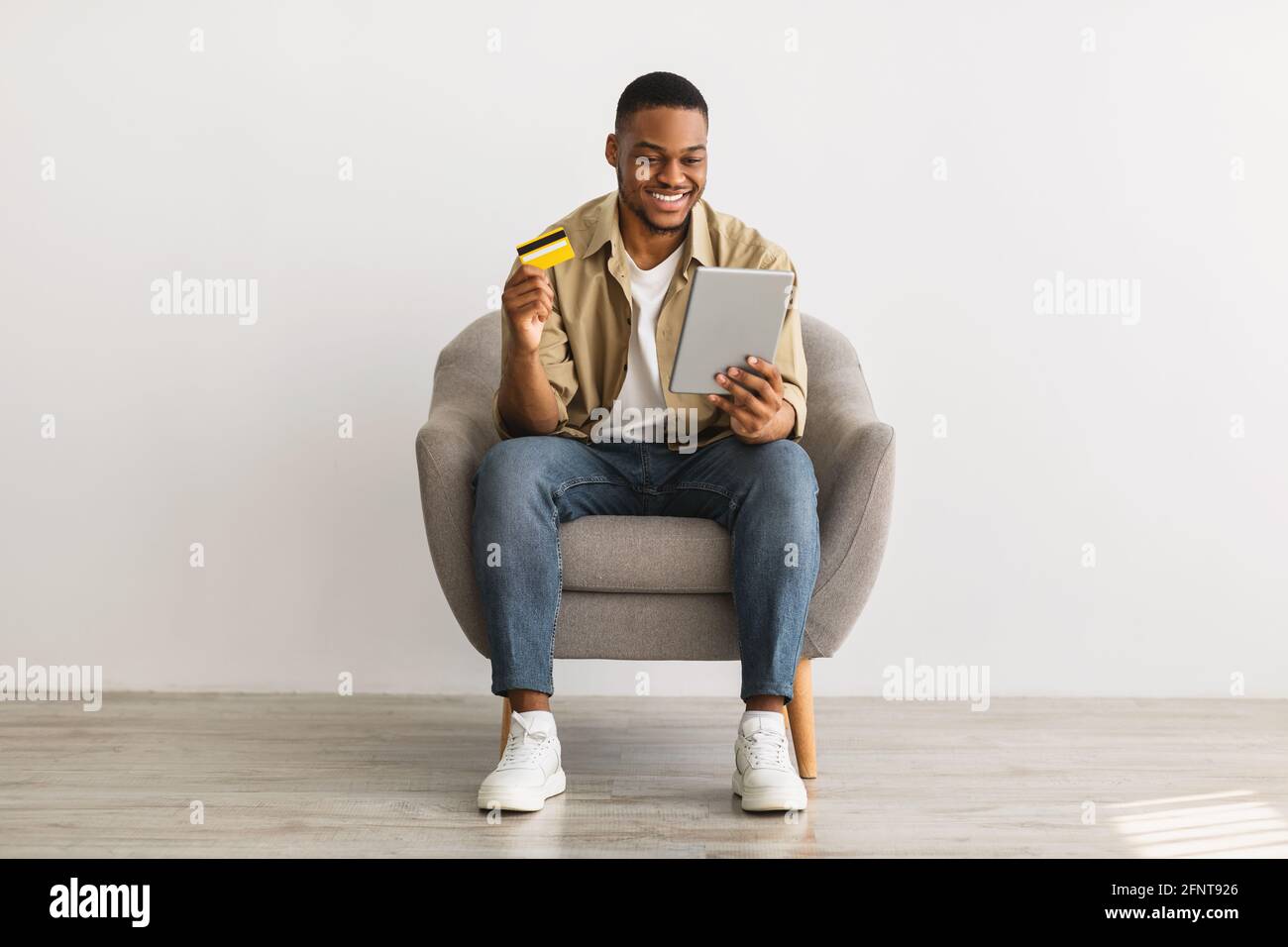 Man Using Tablet And Credit Card Shopping Online, Gray Background Stock Photo