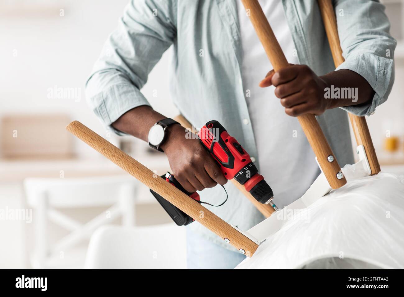 Furniture assembly process. African american handyman screwing legs to ...