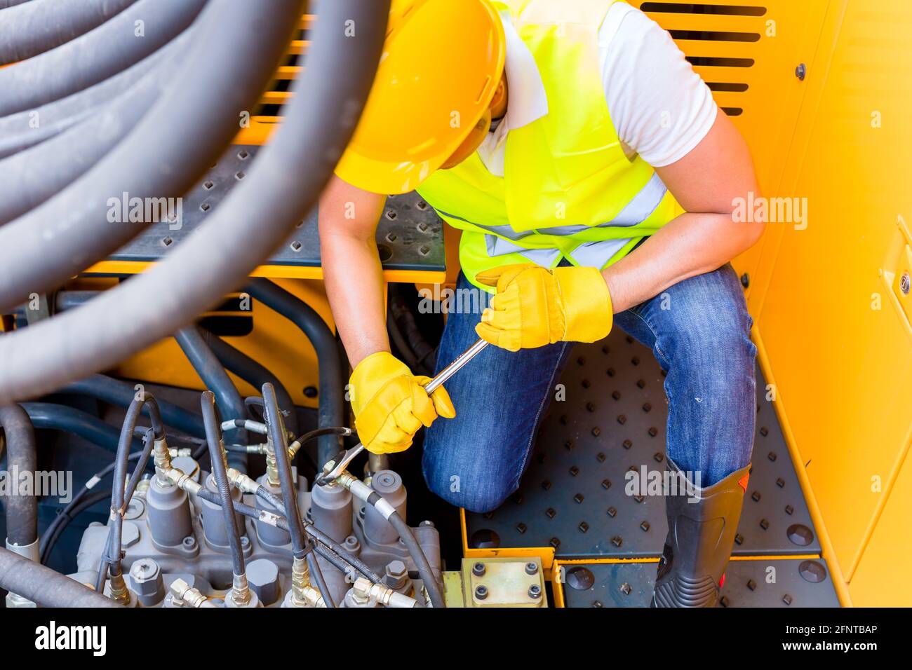 Asian motor mechanic repairing construction or mining machine motor Stock Photo