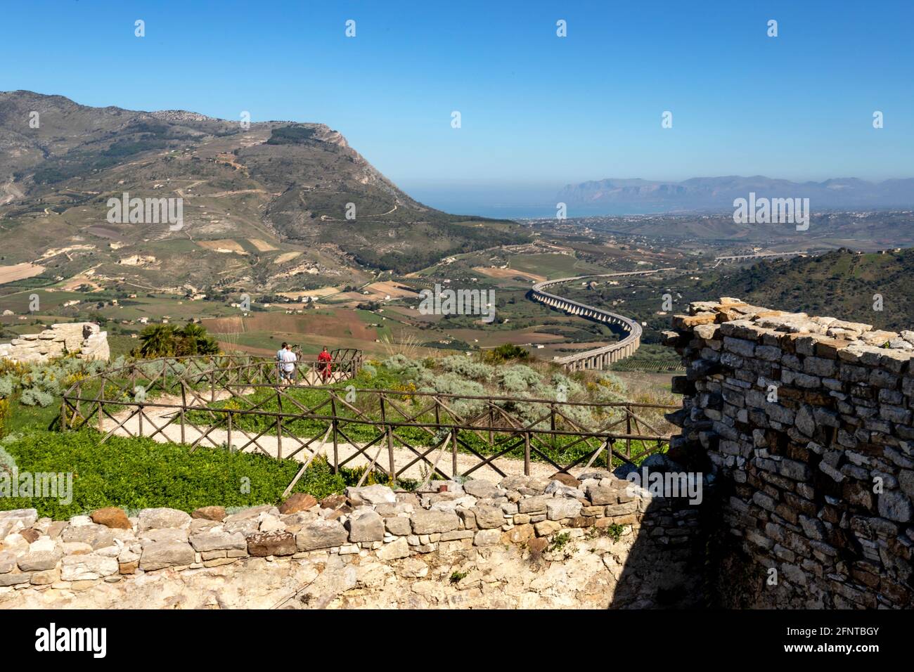 Tourists walking down the trail leading to the Greek theater of Segesta with view of the curved motorway, the Autostrada A29, Trapani, Sicily, Italy. Stock Photo