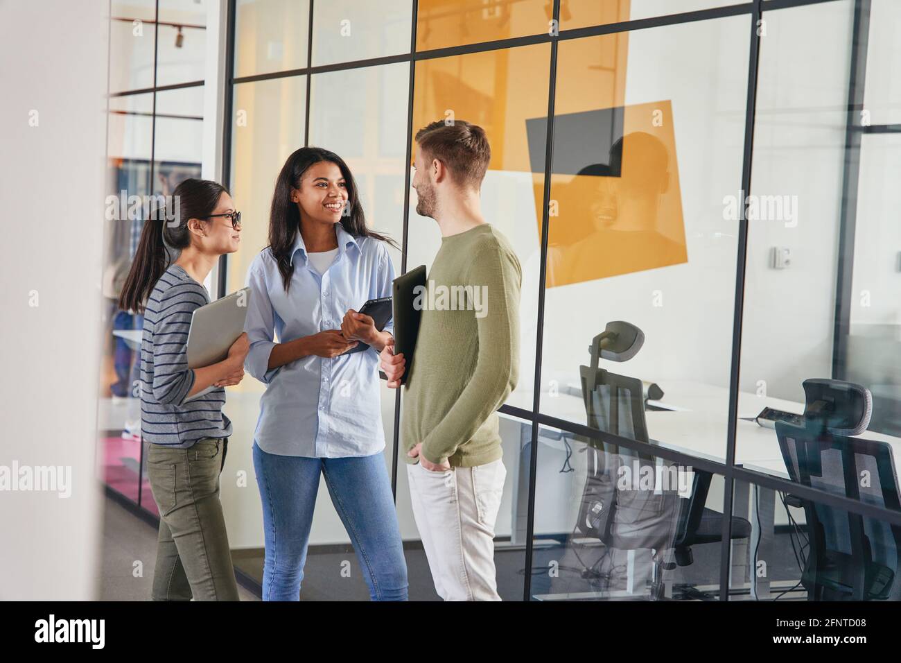 Three coworkers having a conversation in a hallway Stock Photo Alamy