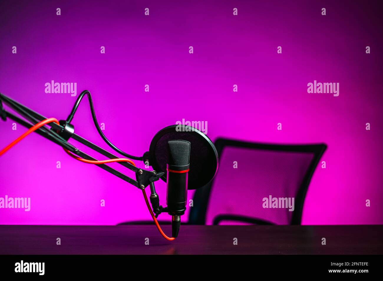 A microphone on the table and a pink backlit armchair. Video blogger workplace Stock Photo