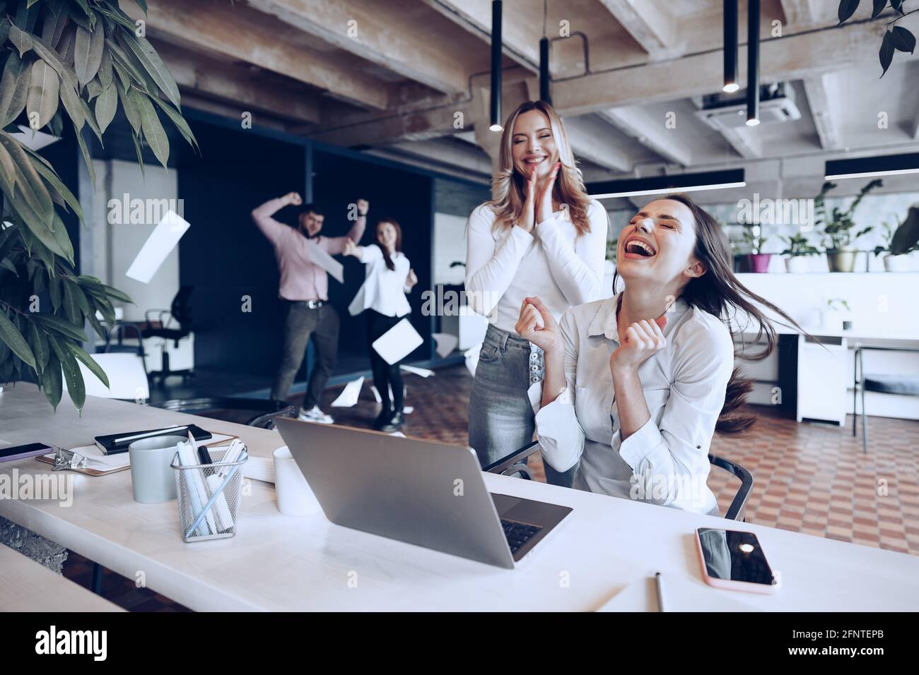 Two young happy businesswomen celebrating project success in office ...