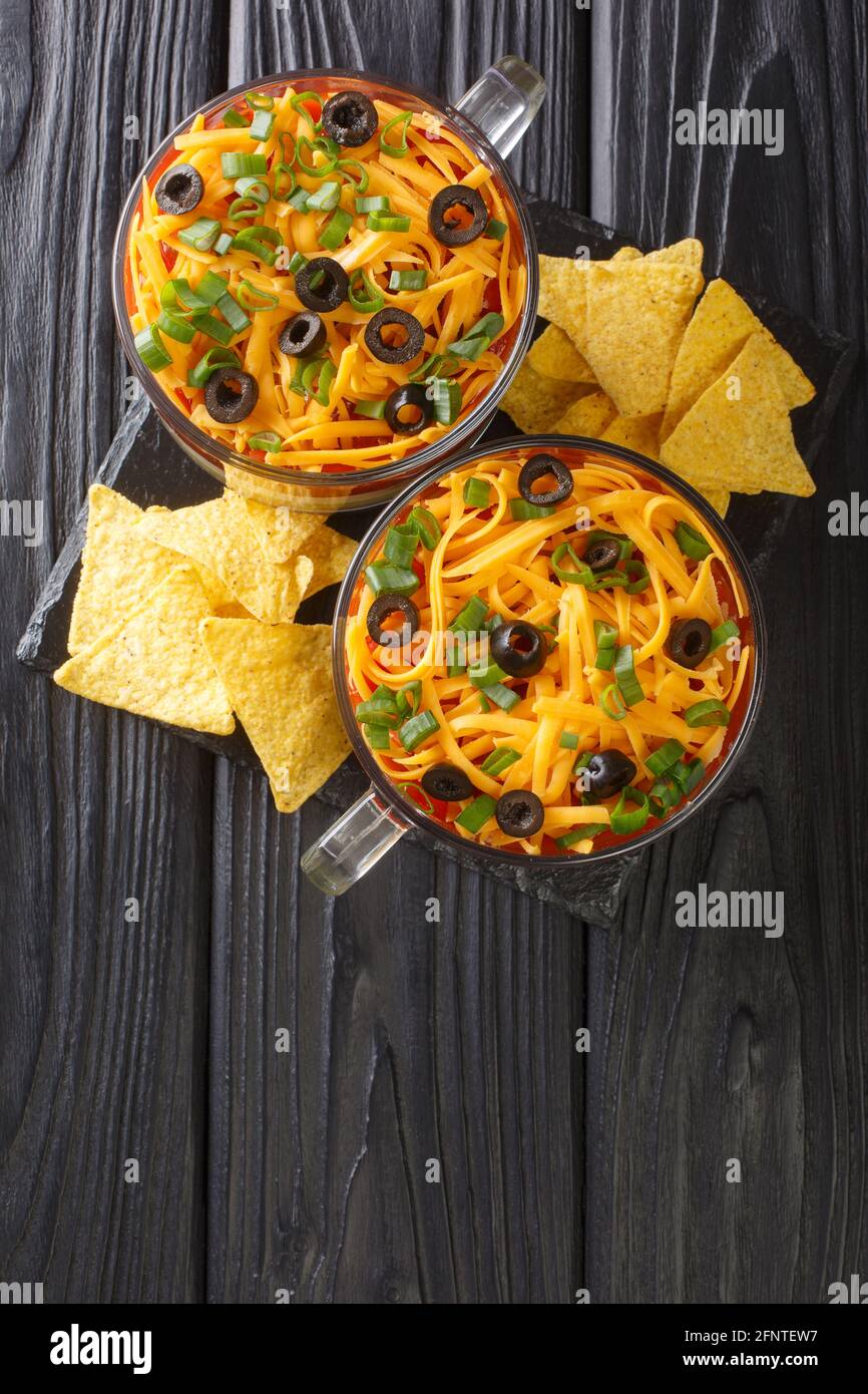Mexican seven layer dip salad served with chips close-up on the table. vertical top view from above Stock Photo