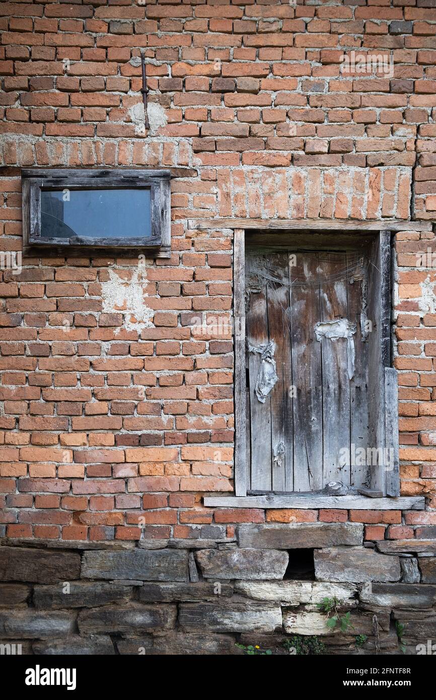 Closed old, rustic, wooden barn door and window on a red brick wall ...