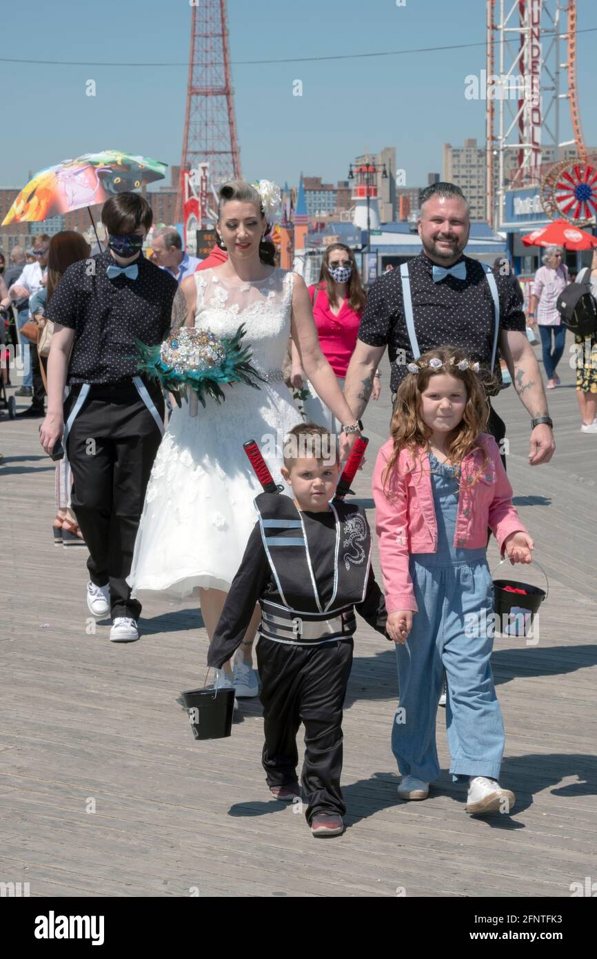 A bride, groom & their wedding party walk on the boardwalk on the way to their wedding on the beach. In Coney Island, Brooklyn, New York City. Stock Photo