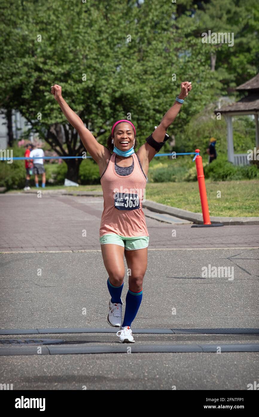 A young lady is jubilant as she approaches the finish line of the NYCRuns Queens half marathon in Flushing Meadows Corona Park in New York City. Stock Photo