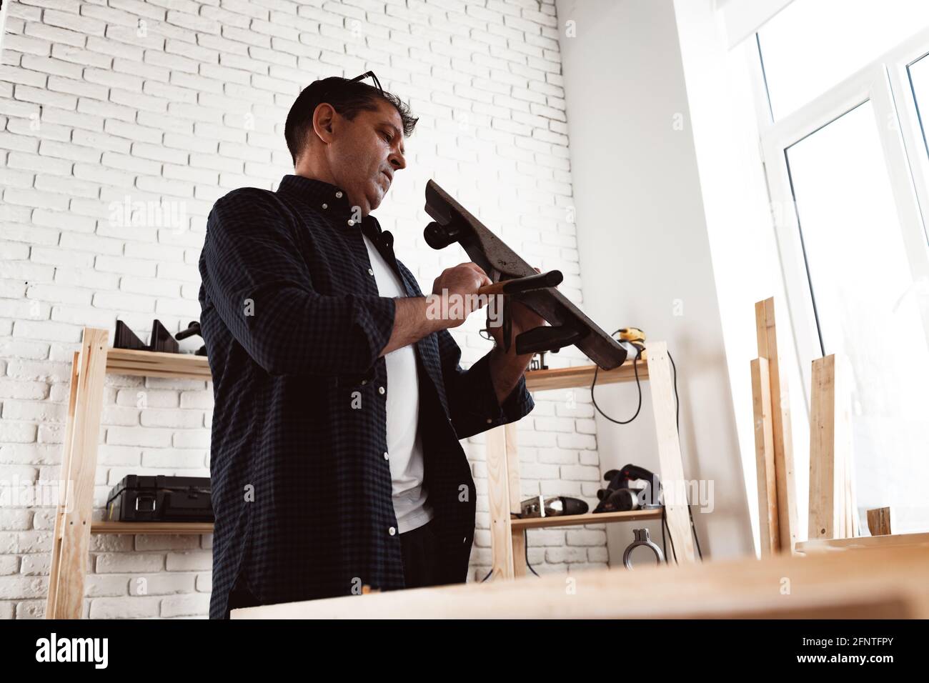 Carpenter's hands planing a plank of wood with a hand plane Stock Photo