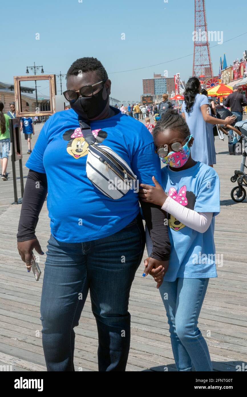 A mother & daughter with matching Minnie Mouse t shirts walk together on the Boardwalk in Coney Island, Brooklyn, New York. Stock Photo