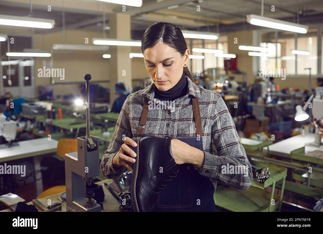 Footwear factory worker checking quality of seams and stitches of newly