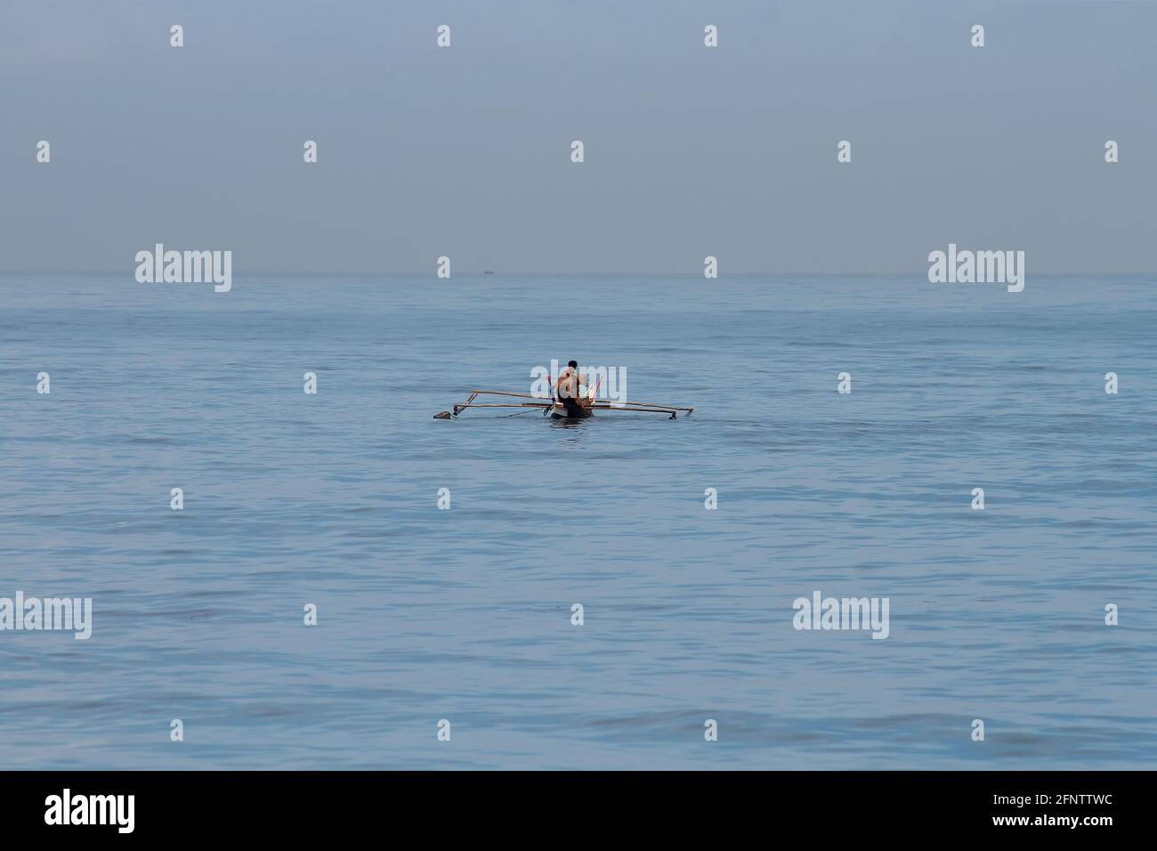 Two fishermen pulling their nets from the sea while fishing by boat in the waters of West Sumatra, Sumatra, Indonesia. Minimalism Stock Photo