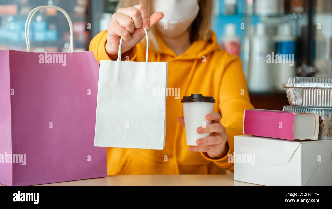 Takeaway food delivery mock up. Food box bag drink coffee to go in takeaway restaurant. Kitchen worker issues online orders in gloves mask Stock Photo
